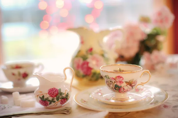 Vintage-Porzellantasse mit Blumenmuster, Milchkanne und Zuckerwürfel